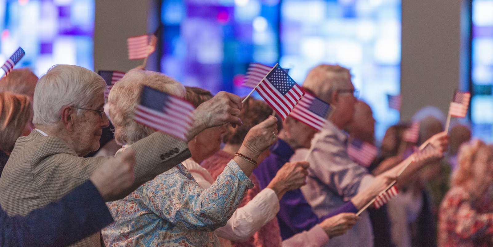 older Americans holding up mini American flags